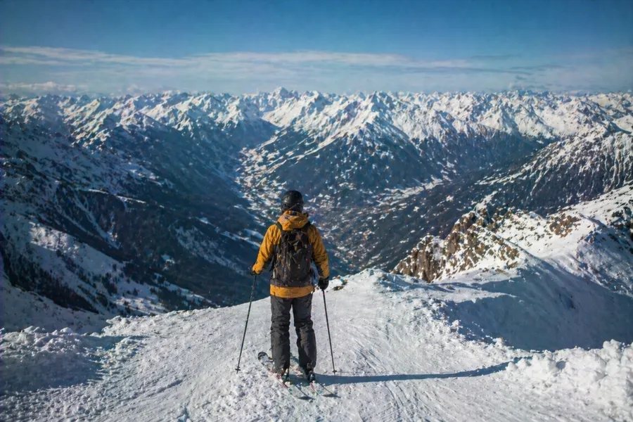 Esquiador contemplando el panorama de cordilleras nevadas desde la cima