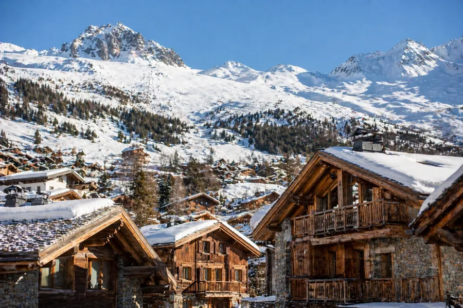 Chalets suizos de Verbier con tejados nevados y pistas visibles al fondo