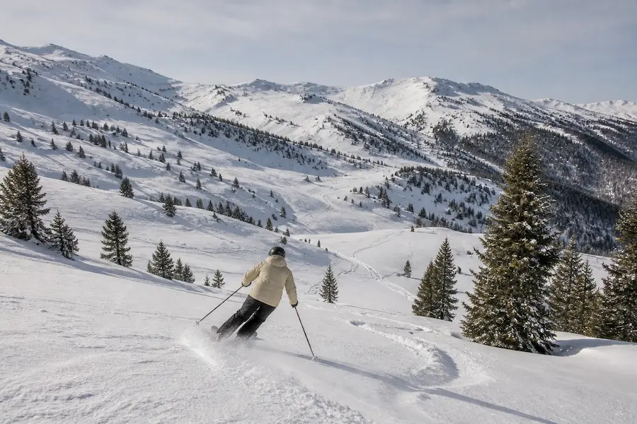 Esquiador descendiendo fuera de pista suave en Baqueira Beret con pinos en el Pirineo