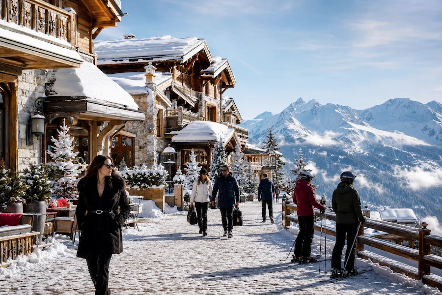Paseo nevado en Courchevel con chalets de lujo, ambiente après-ski elegante y vistas a las montañas de los Alpes franceses.