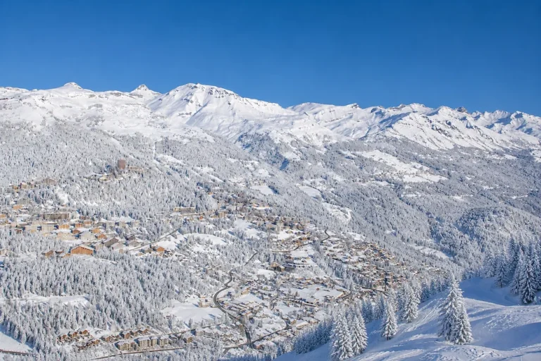 Vista panorámica de Crans-Montana con bosque alpino cubierto de nieve y montañas del Valais suizo al fondo