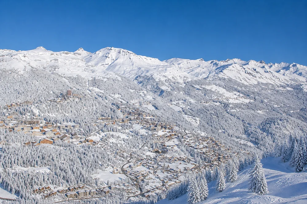 Vista panorámica de Crans-Montana con bosque alpino cubierto de nieve y montañas del Valais suizo al fondo