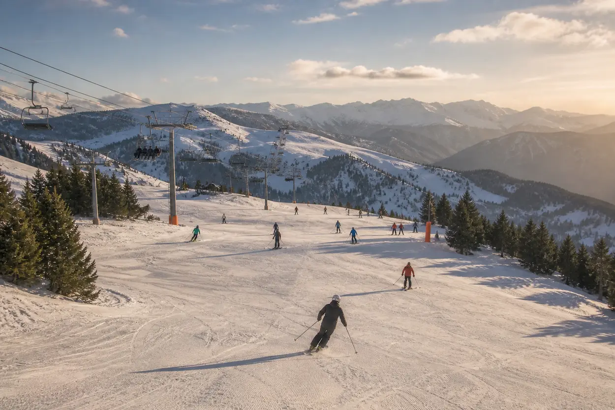 Esquiadores en Baqueira Beret al atardecer con luz dorada en los Pirineos