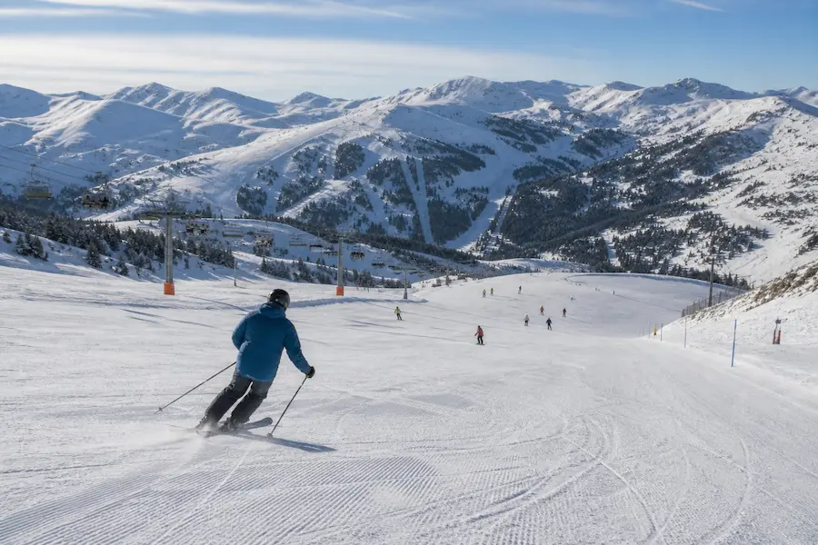 Esquiador descendiendo una pista amplia en Grandvalira Andorra con varios esquiadores y remontes