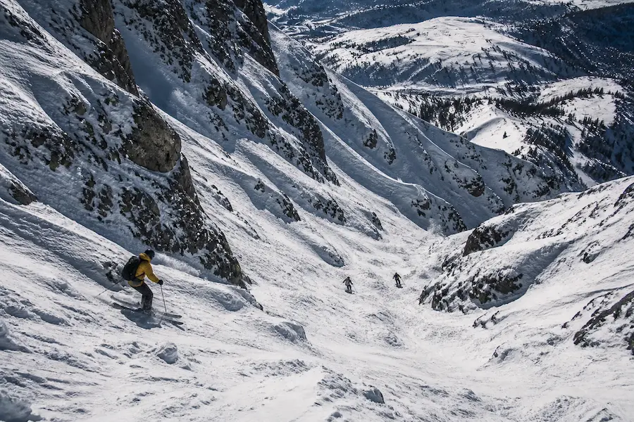 Esquiadores descendiendo terreno empinado e irregular en Jackson Hole con nieve variable y rocas expuestas