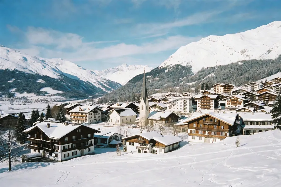 Pueblo tradicional de Kitzbühel con iglesia y montañas nevadas