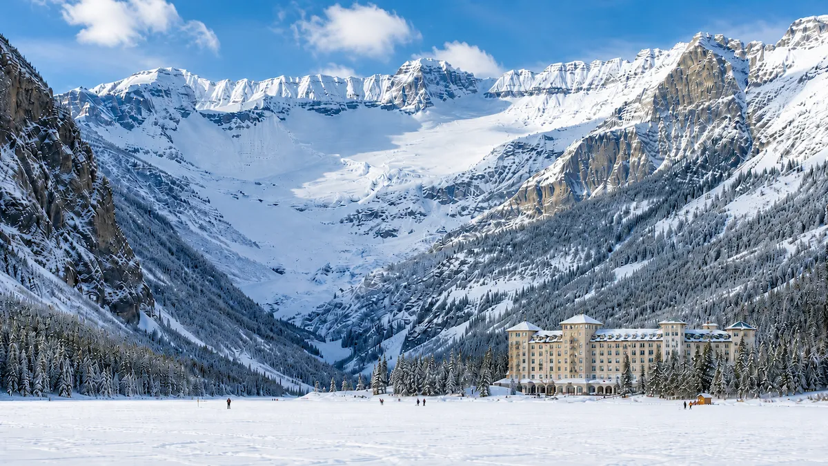 Lake Louise en invierno, con el Fairmont Chateau Lake Louise frente al lago congelado y el glaciar al fondo bajo luz diurna.