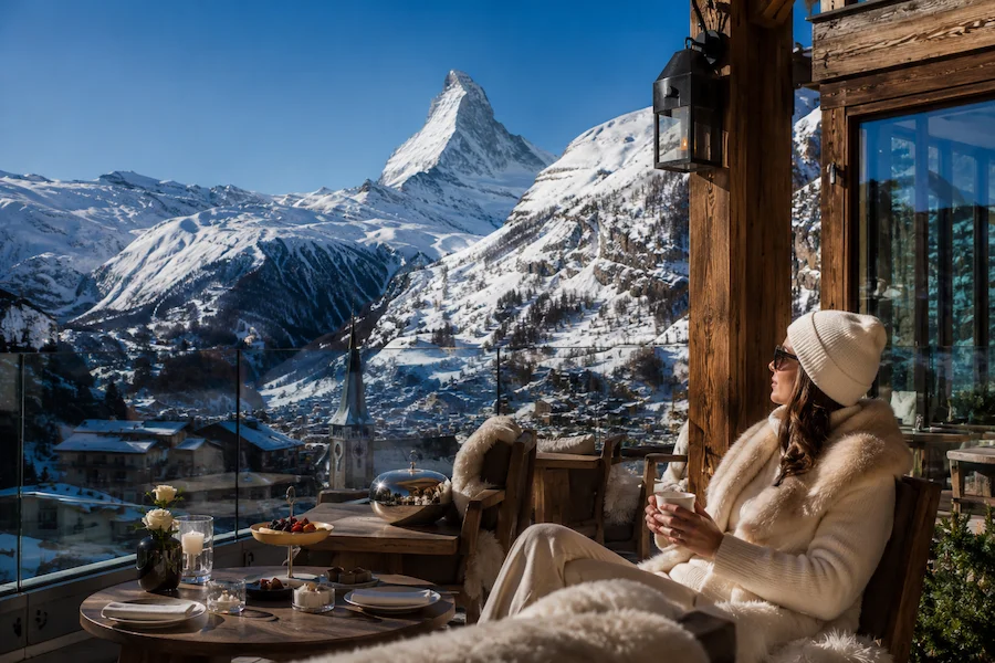 Terraza de hotel de lujo en Zermatt con vista al Matterhorn y una huésped disfrutando del paisaje nevado