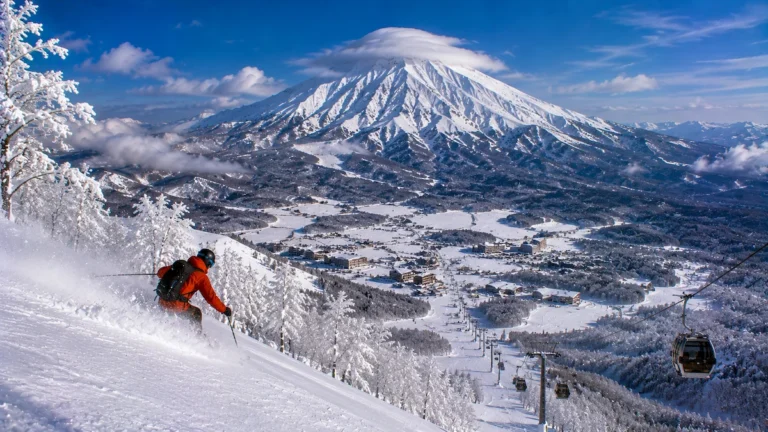 Esquiador descendiendo en Myoko Kogen con nieve profunda, bosque helado y el volcán Myoko-san dominando el paisaje japonés.