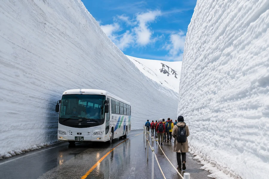 Bus atravesando paredes de nieve en la ruta alpina de Japón durante un viaje de invierno