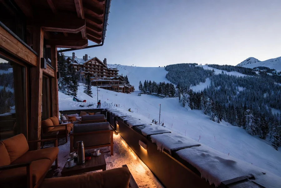 Terraza de hotel ski-in ski-out junto a pistas nevadas al atardecer
