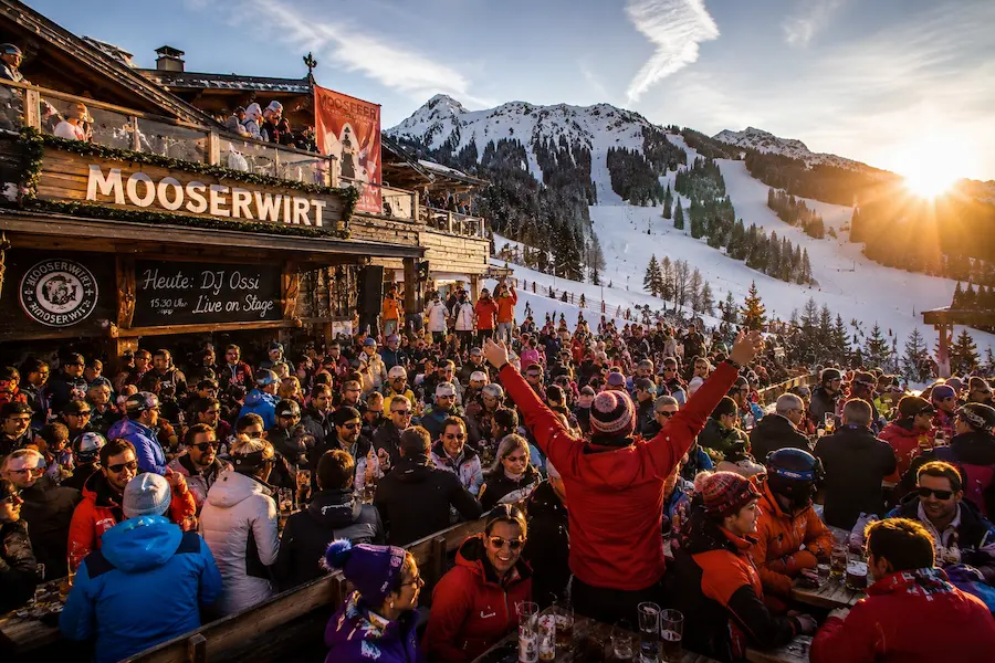 Ambiente de après-ski en Mooserwirt St. Anton con esquiadores y terraza llena