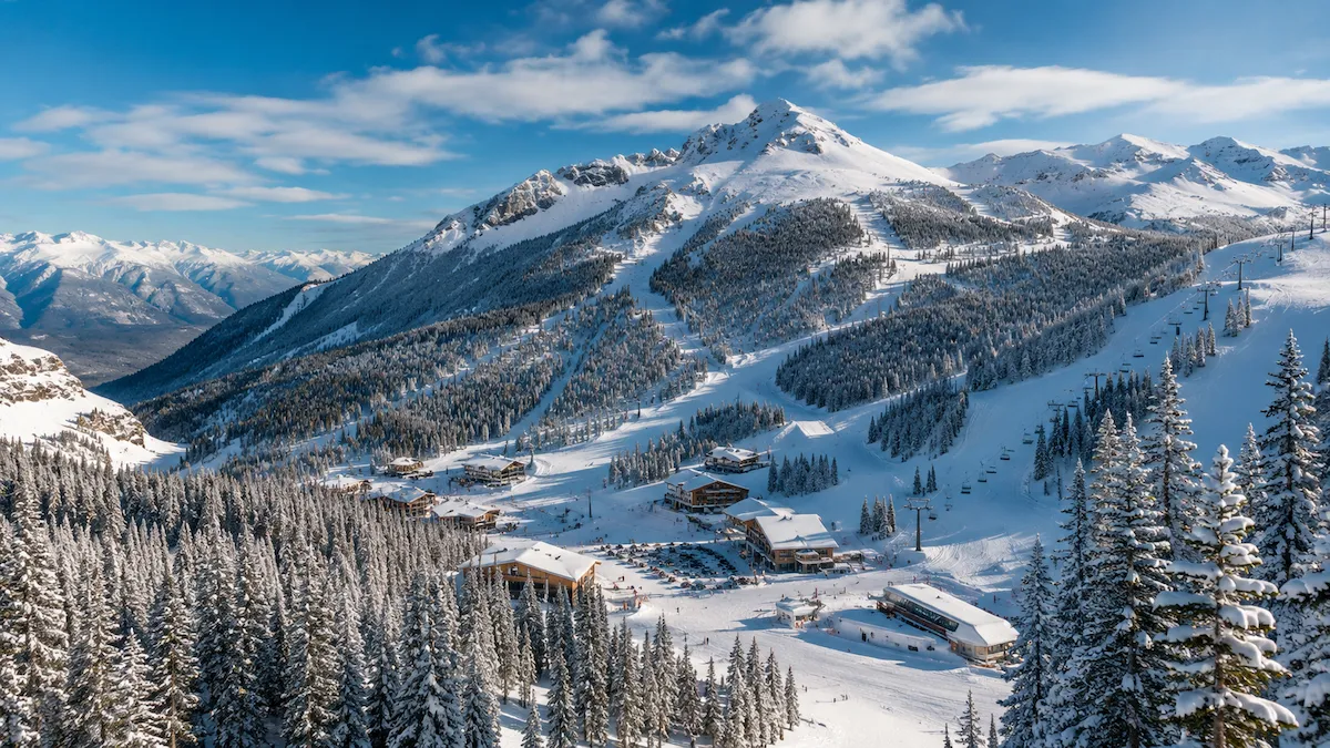 Vista panorámica de Sunshine Village en Banff, con pistas entre bosque nevado, remontes y montañas de las Rocosas al fondo.