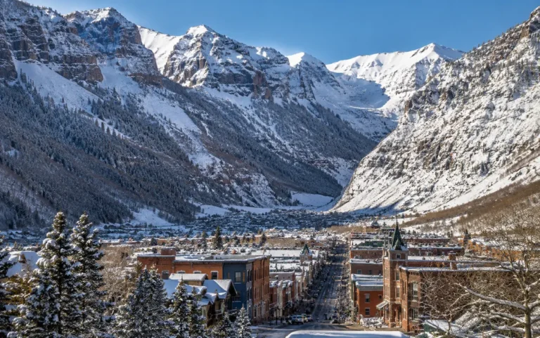 Pueblo nevado de Telluride encajado entre montañas de Colorado, con calles históricas y grandes picos alpinos al fondo.