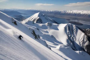 Esquiador en Treble Cone sobre el lago Wanaka en un terreno abierto de Nueva Zelanda.