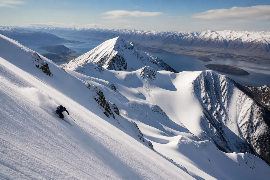 Esquiador en Treble Cone sobre el lago Wanaka en un terreno abierto de Nueva Zelanda