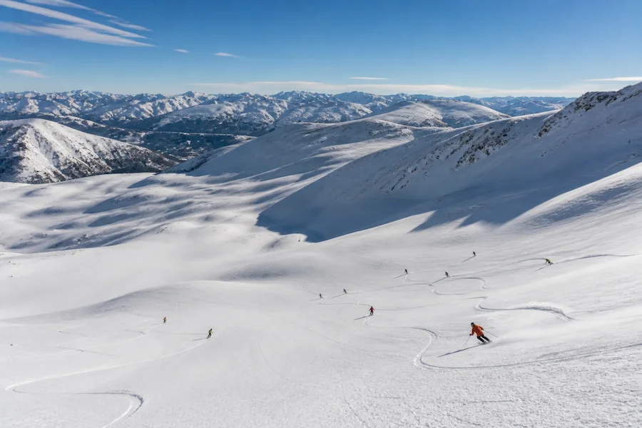 Esquiadores descendiendo los back bowls de Vail con terreno amplio y nieve seca bajo cielo despejado