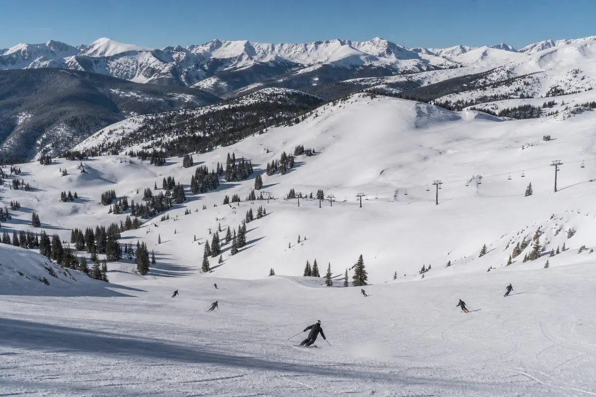 Esquiadores descendiendo en los back bowls de Vail con terreno amplio y suave en una estación de esquí en Colorado