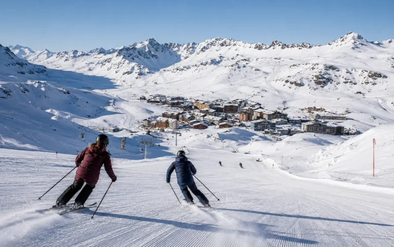 Esquiadores descendiendo hacia Val Thorens, con el pueblo rodeado de nieve y grandes montañas de alta altitud en los Alpes.